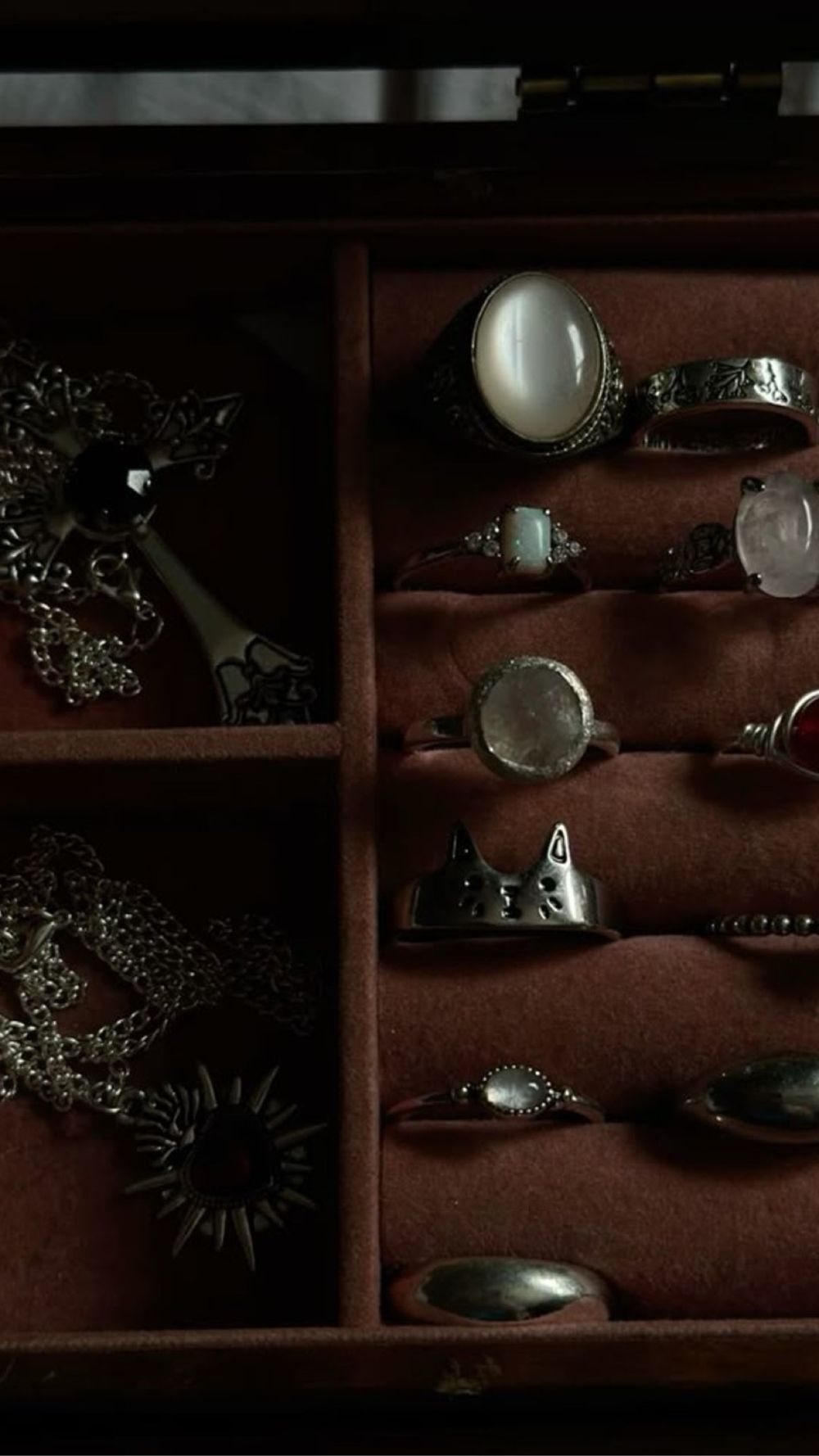 Silver moonstone rings and gothic pendants arranged in a velvet jewelry box